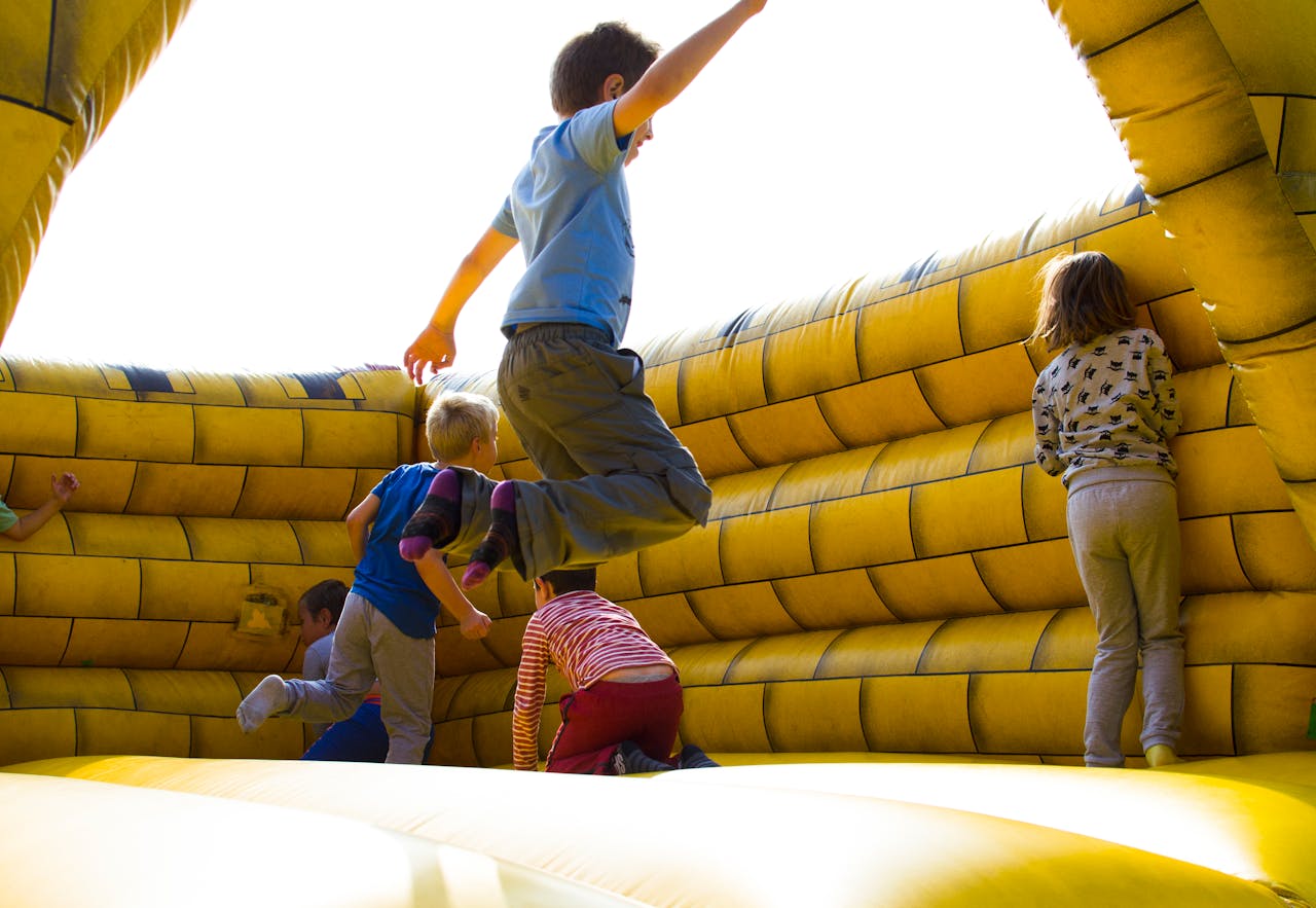 our-services-04 Kids enjoying a fun time bouncing in a vibrant inflatable castle outdoors.