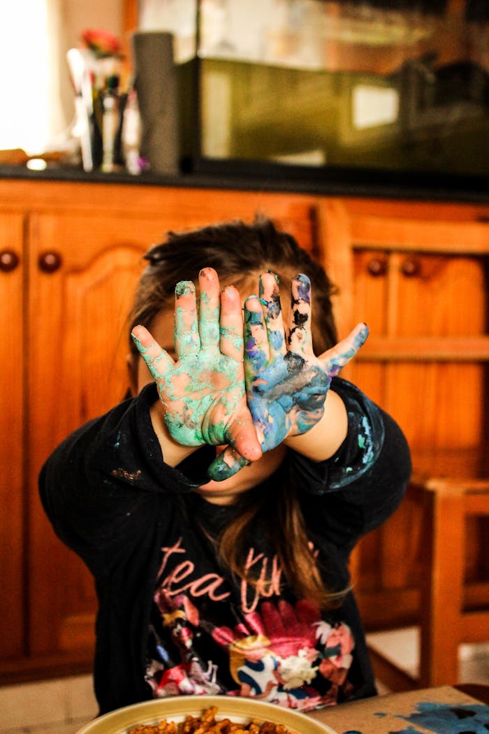 our-services-05 A child shows colorful painted hands during a fun and messy indoor art project.